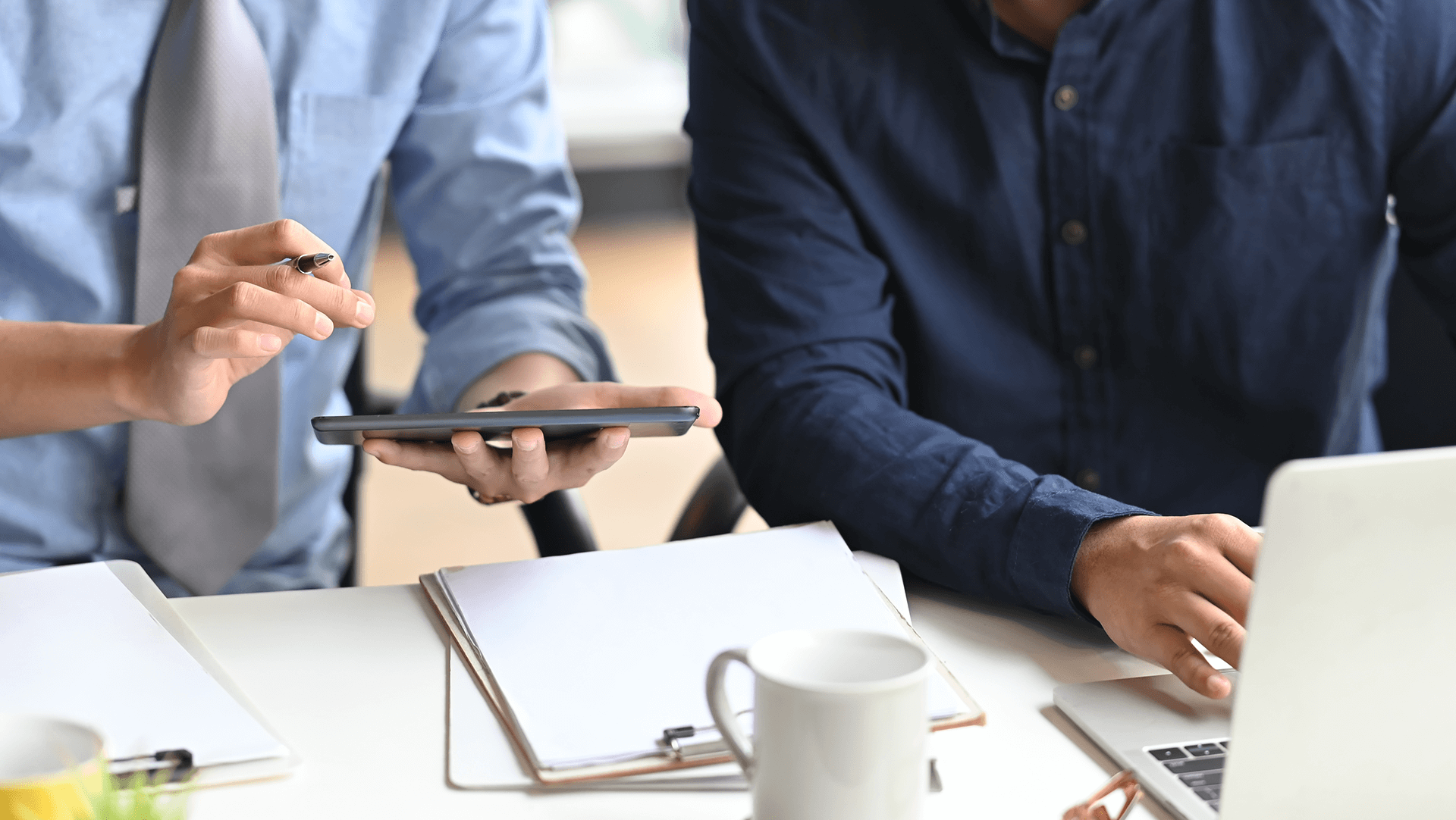 Two professionals collaborating at a workspace with digital devices and documents.