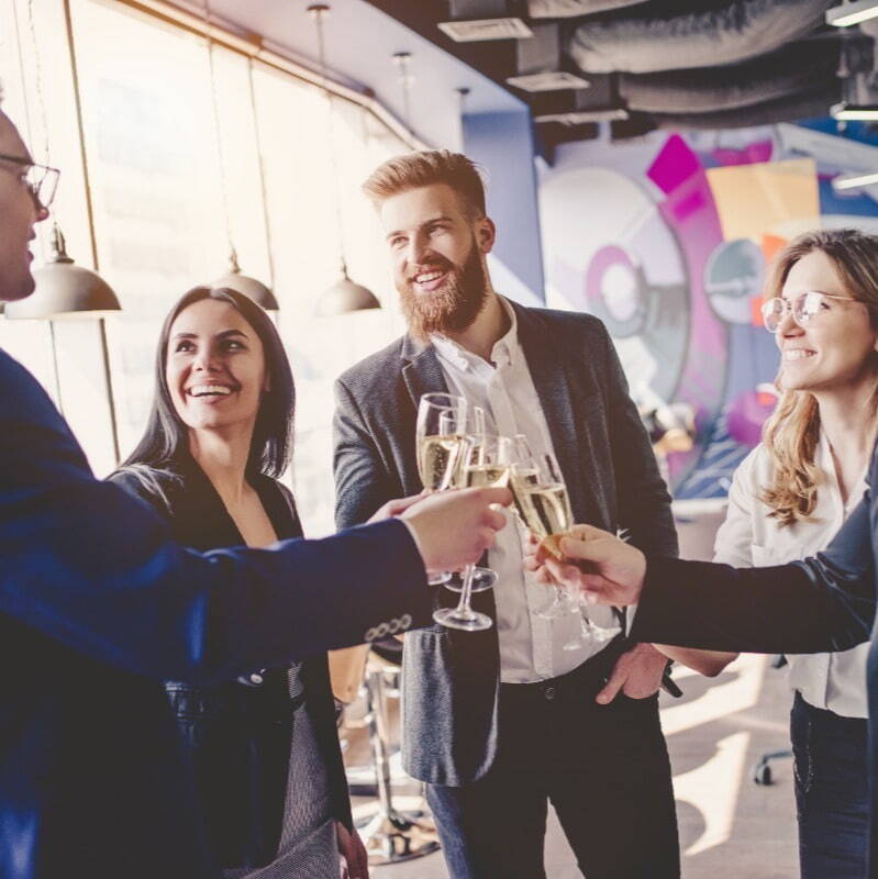 a group of people dressed professionally celebrating with glasses of champagne